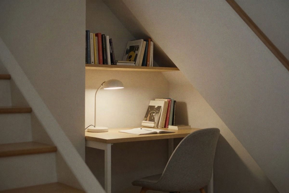 Illustrative image: Small desk under the stairs with focused lighting and organized books.