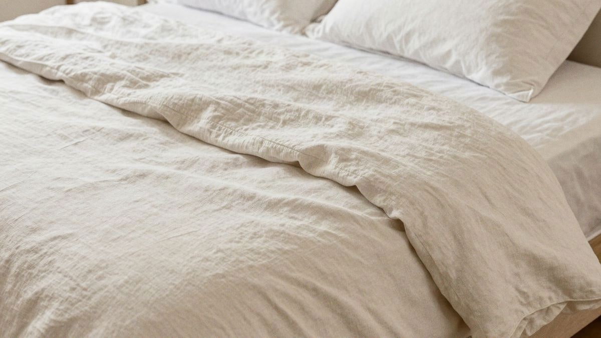 Illustrative image: close-up of cream and white folded linen sheets showing natural texture