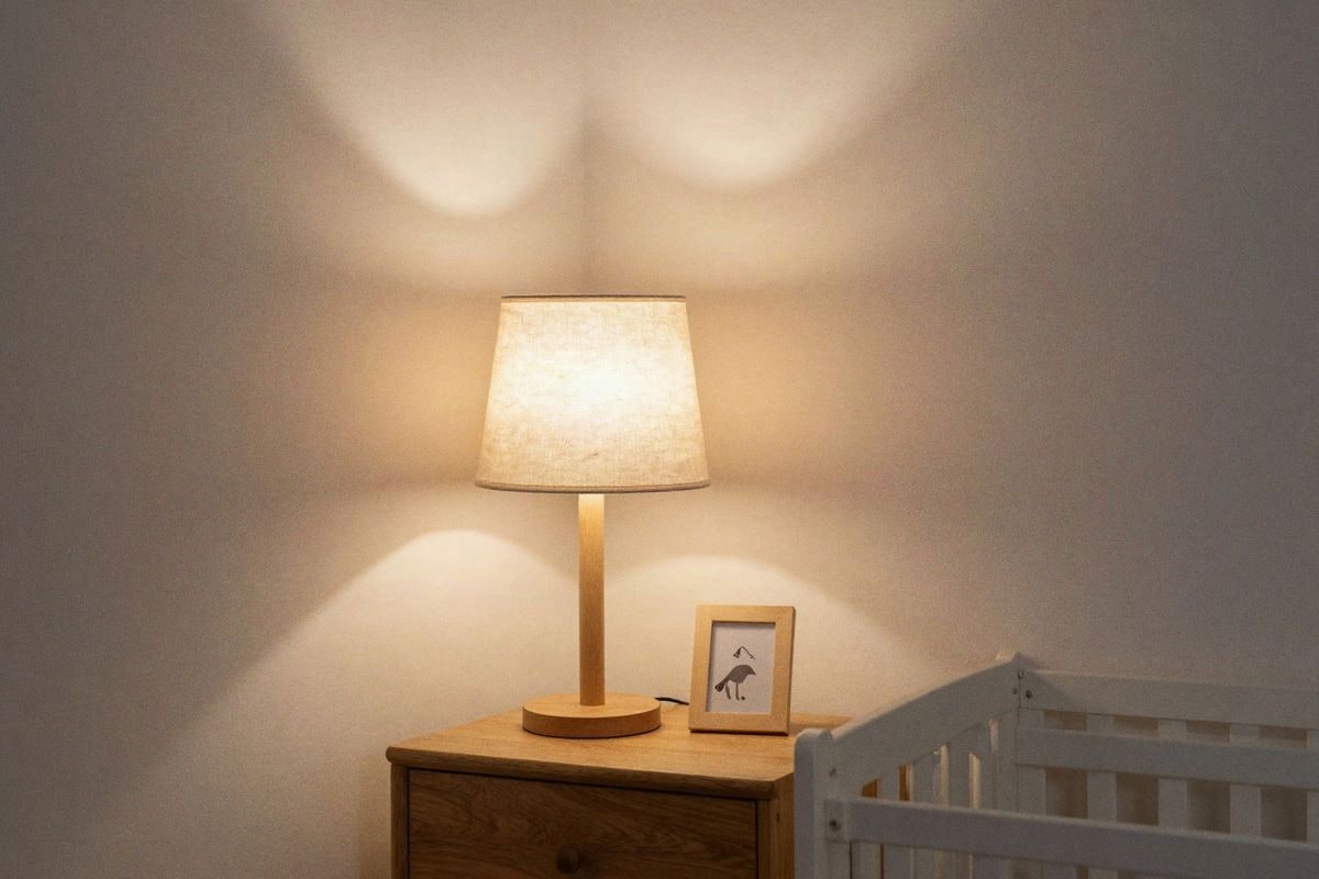 Imagen ilustrativa: Rincón acogedora de habitación bebé con iluminación suave y lámpara minimalista.