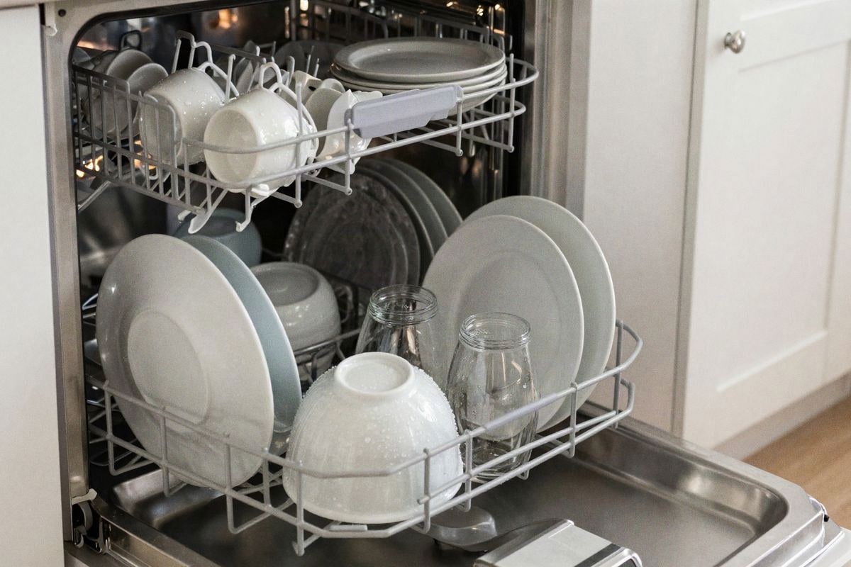 Illustrative image: compact dishwasher interior properly loaded with dishes, glasses and utensils well distributed.